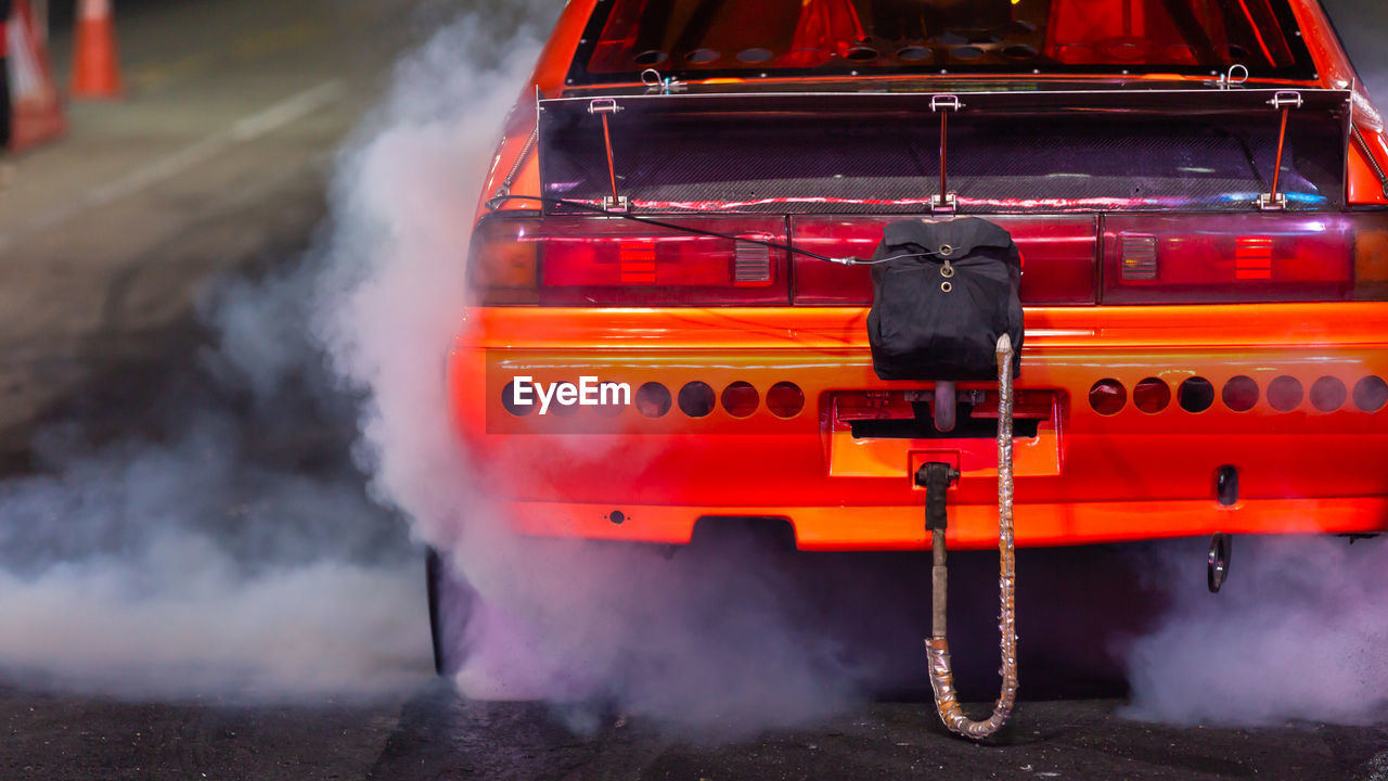 Orange drag car burnout wheels with smoke, drag racing car burnout wheel rubber off its tires.