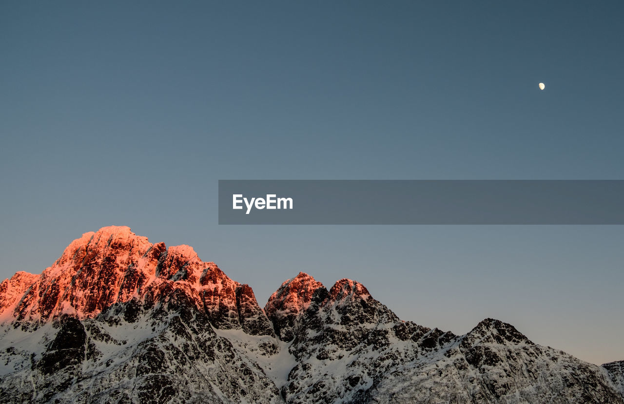 Low angle view of snowcapped mountains against clear sky