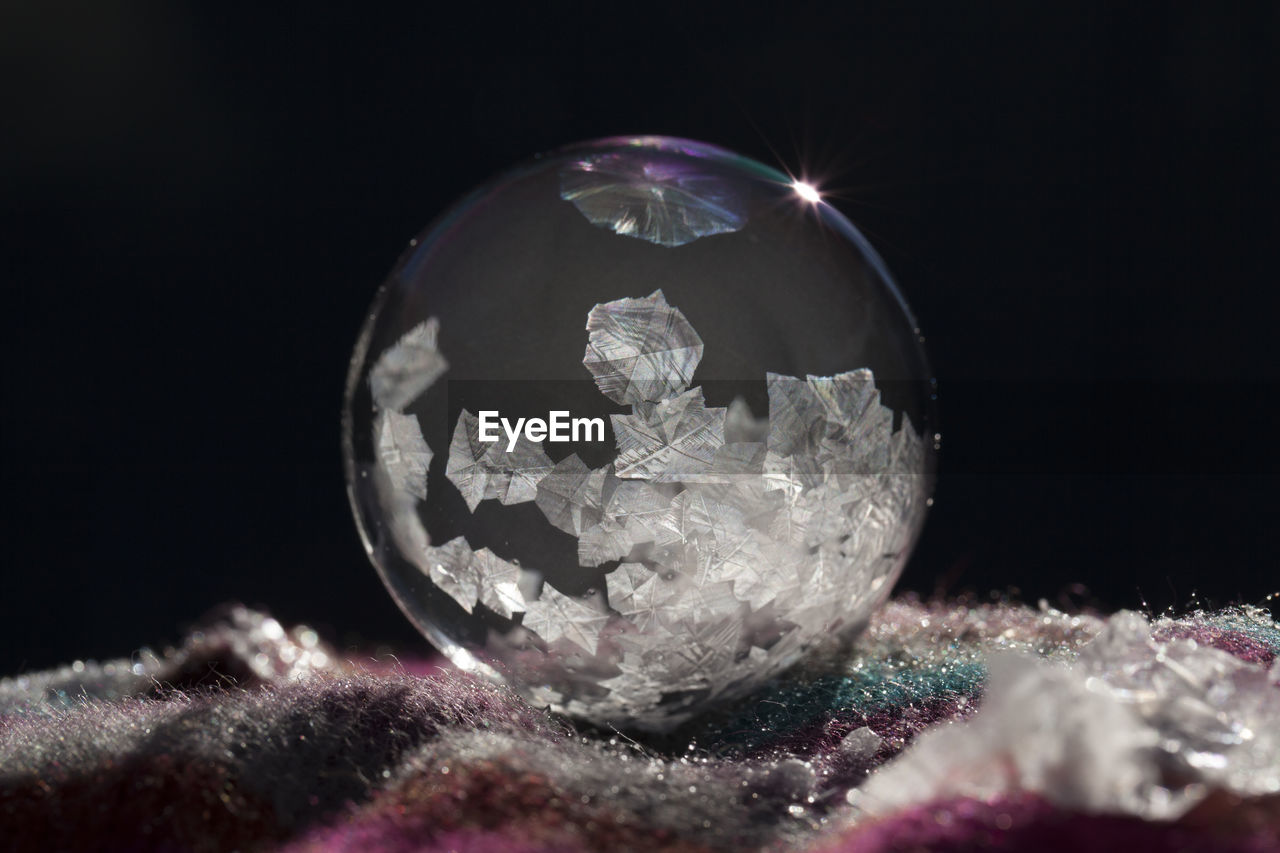 CLOSE-UP OF CRYSTAL BALL WITH REFLECTION OF LIGHT IN WATER