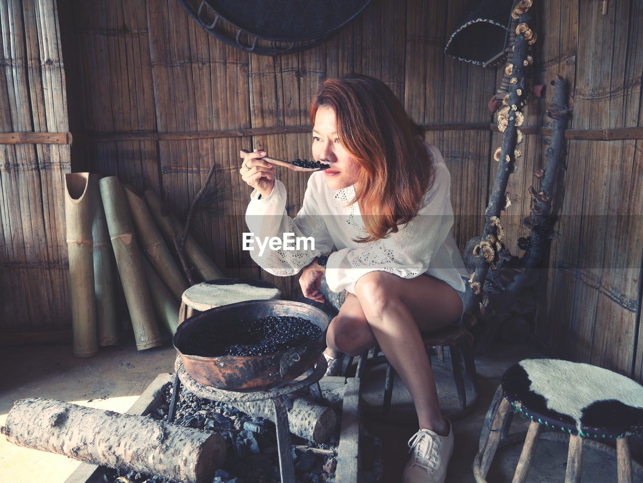 Woman smelling roasted coffee beans while sitting in hut
