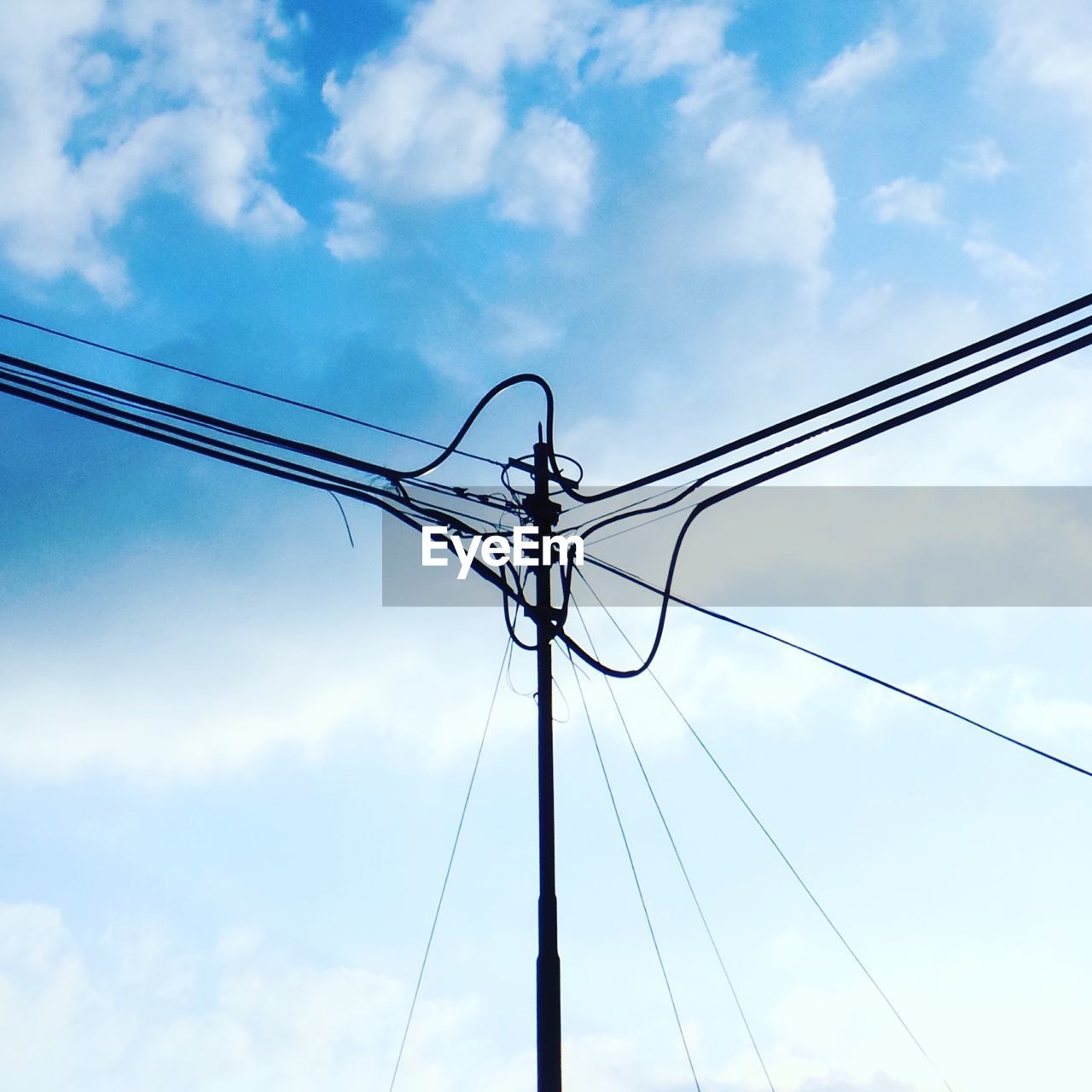 Low angle view of silhouette cables against cloudy sky