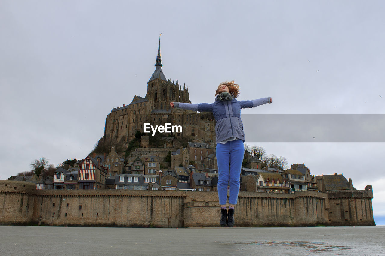 Woman in jump against the mont saint michel in france