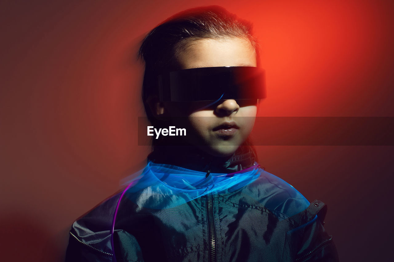 Portrait cyberpunk boy child in vr glasses in blue and red tones with wires. game, virtual reality