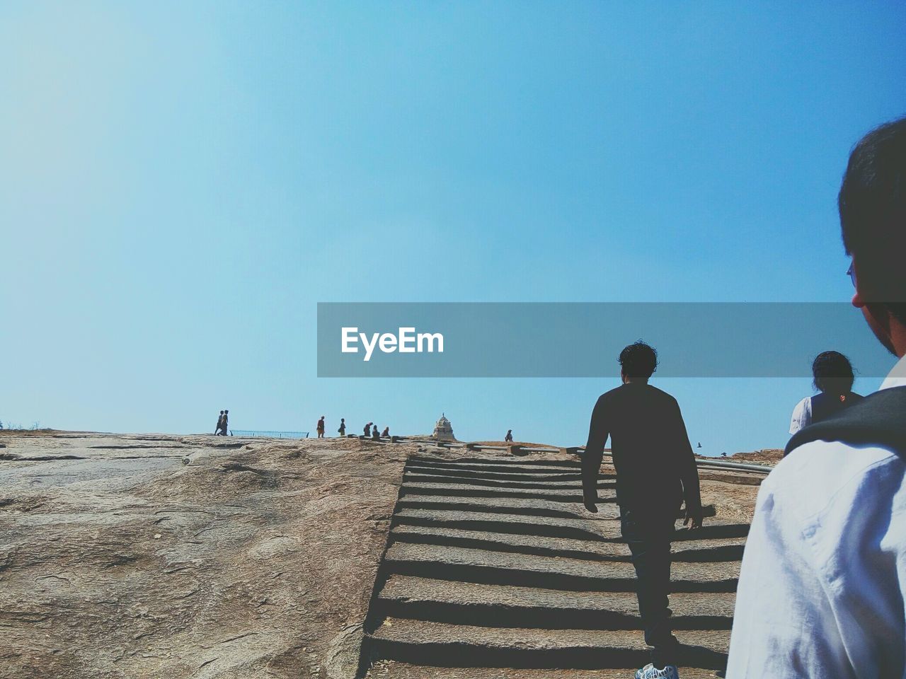 Low angle view of people moving up on steps against clear blue sky