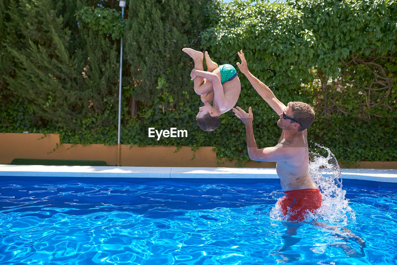 Summer vacation. father and son play in a pool.
