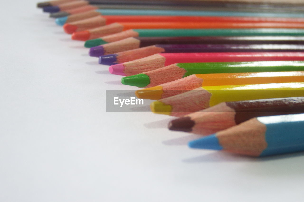 CLOSE-UP OF COLORED PENCILS ON WHITE TABLE