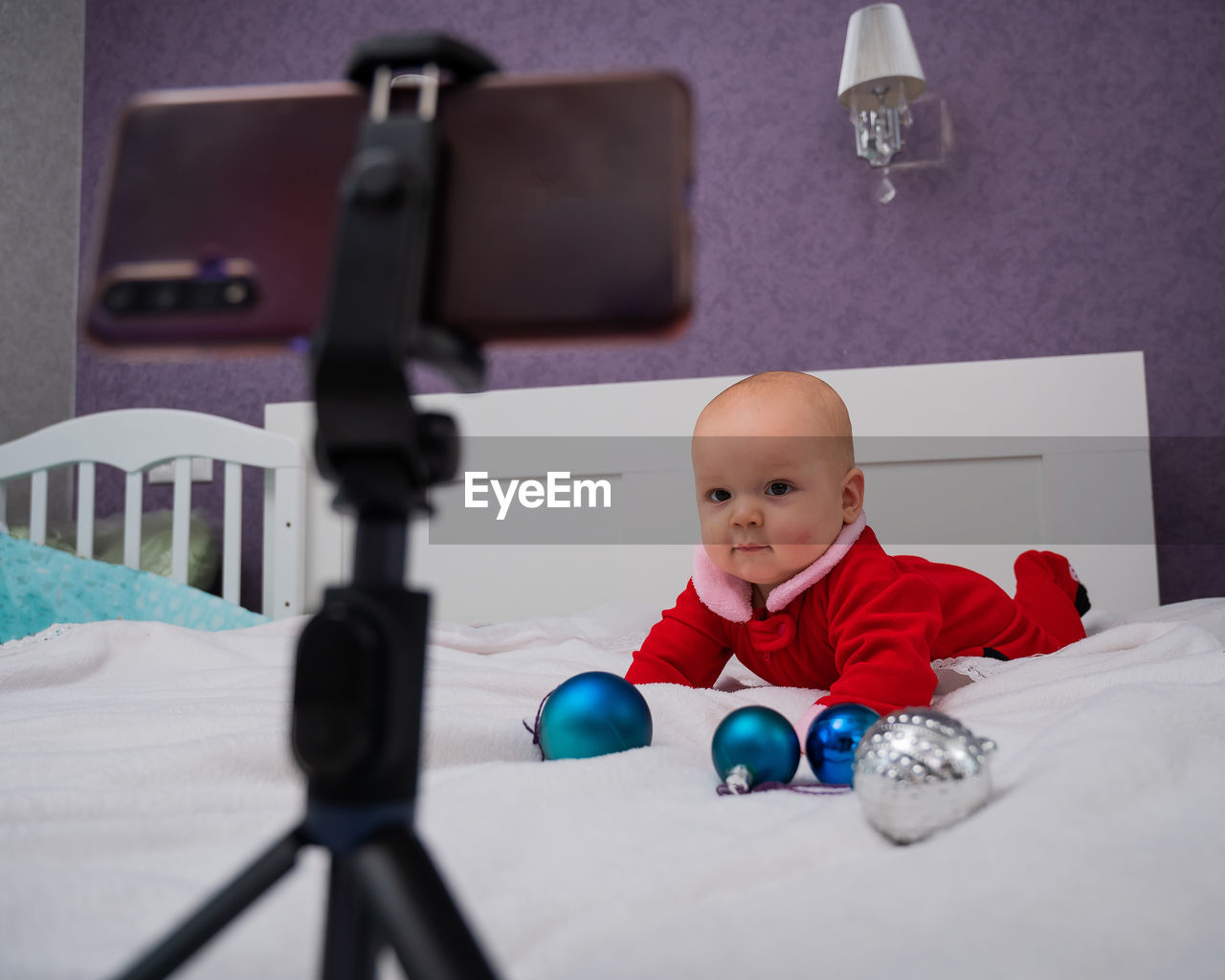 Cute baby looking at mobile phone mounted on tripod