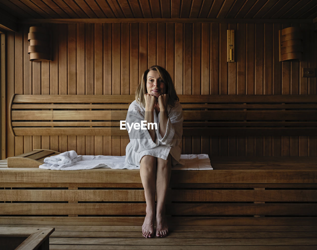 Senior woman with hand on chin sitting on wooden sauna