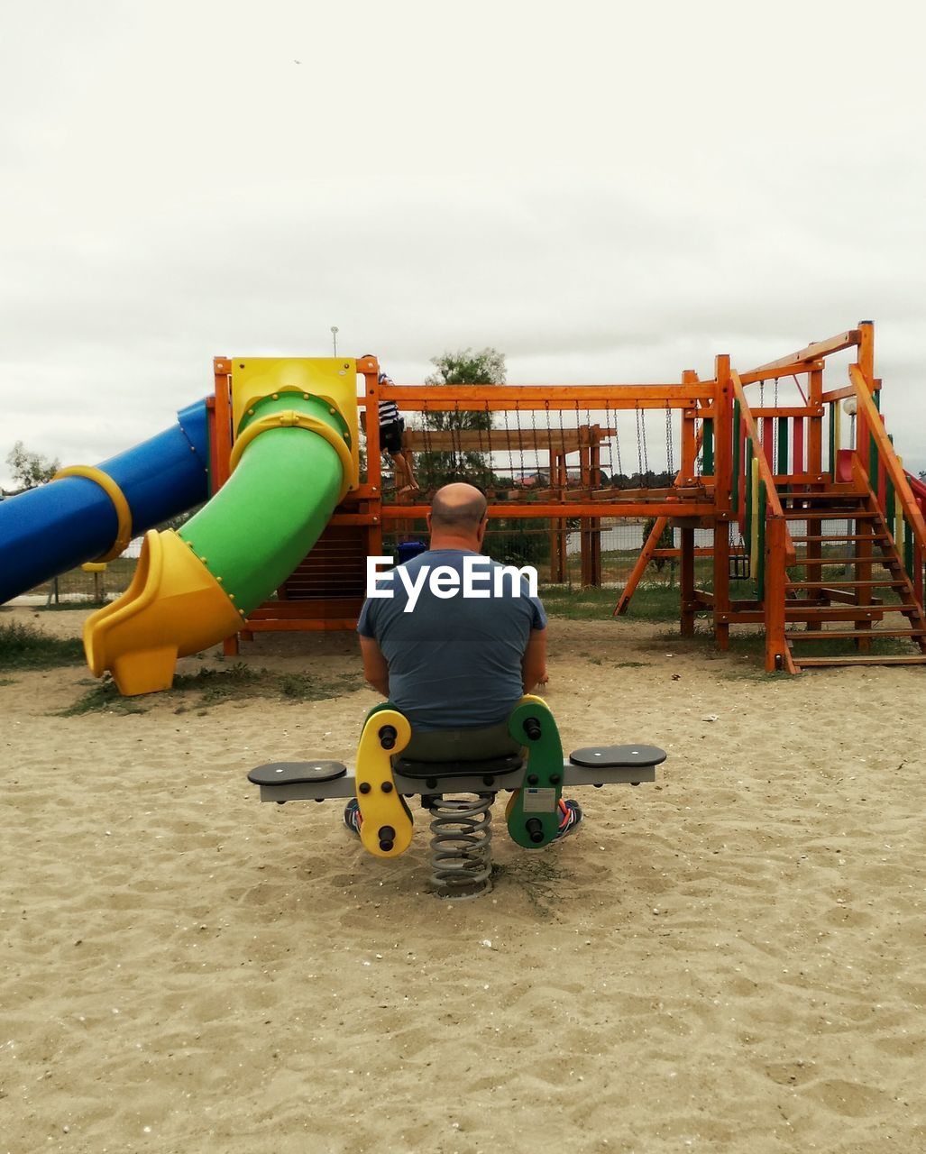 Rear view of man sitting on spring ride at playground