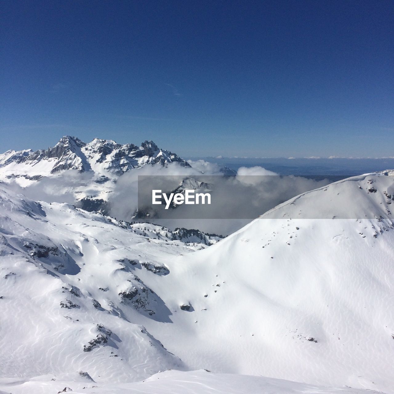 Scenic view of snowcapped mountains against blue sky