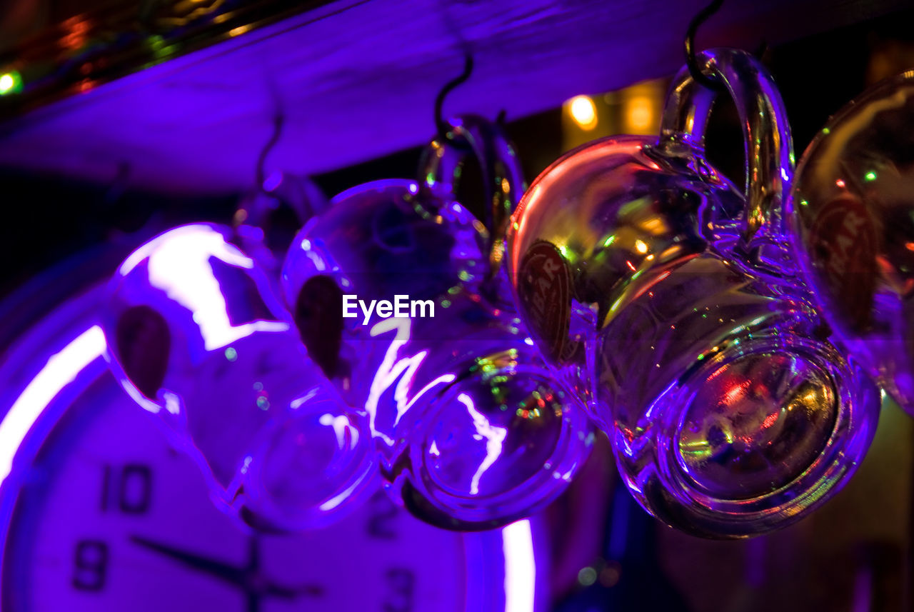 Close-up of drinking glasses hanging in darkroom