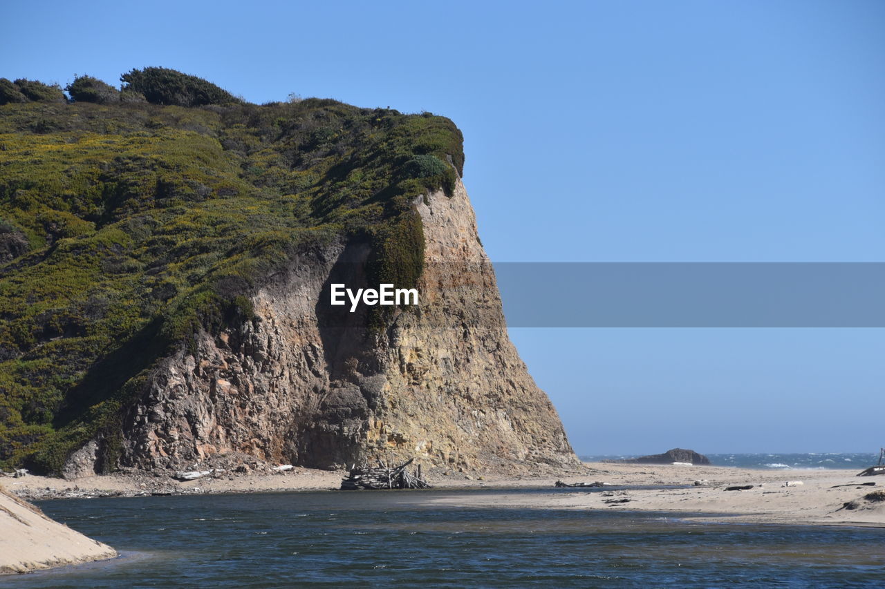 Rock formations on shore against clear sky