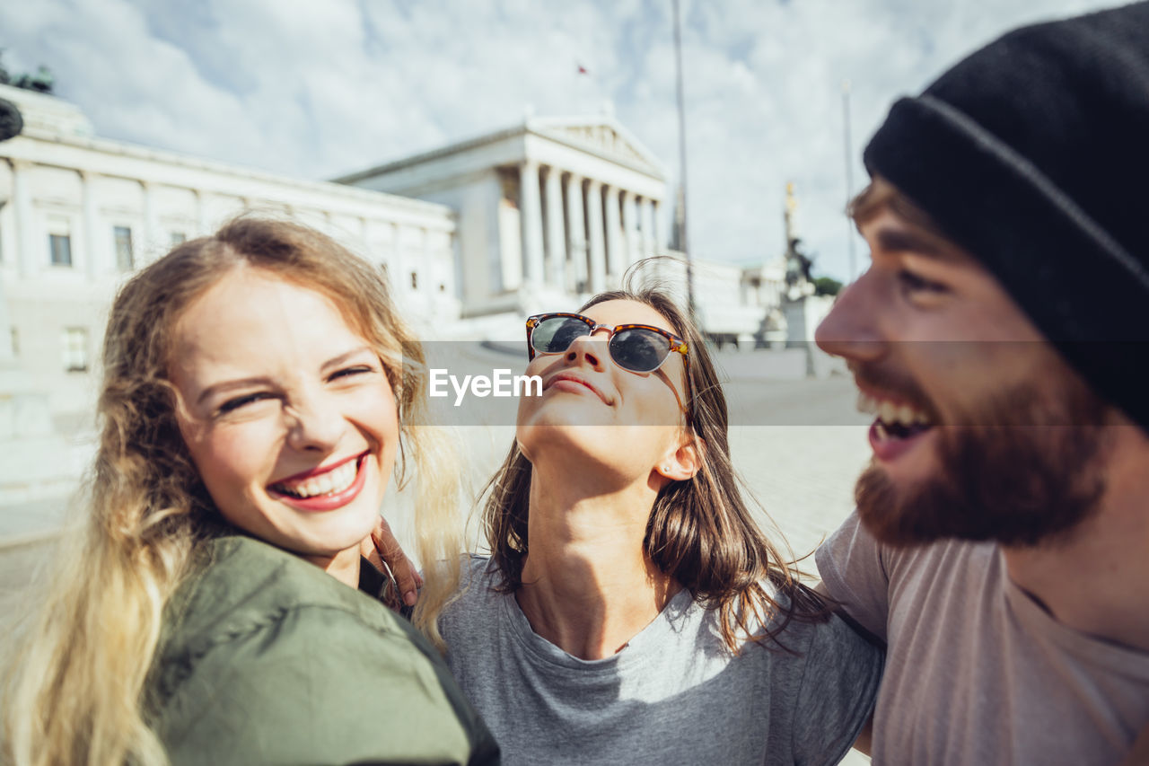 Austria, vienna, three friends having fun in front of the parliament building