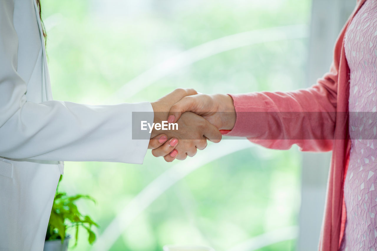 CLOSE-UP OF HAND HOLDING HANDS AGAINST CURTAIN