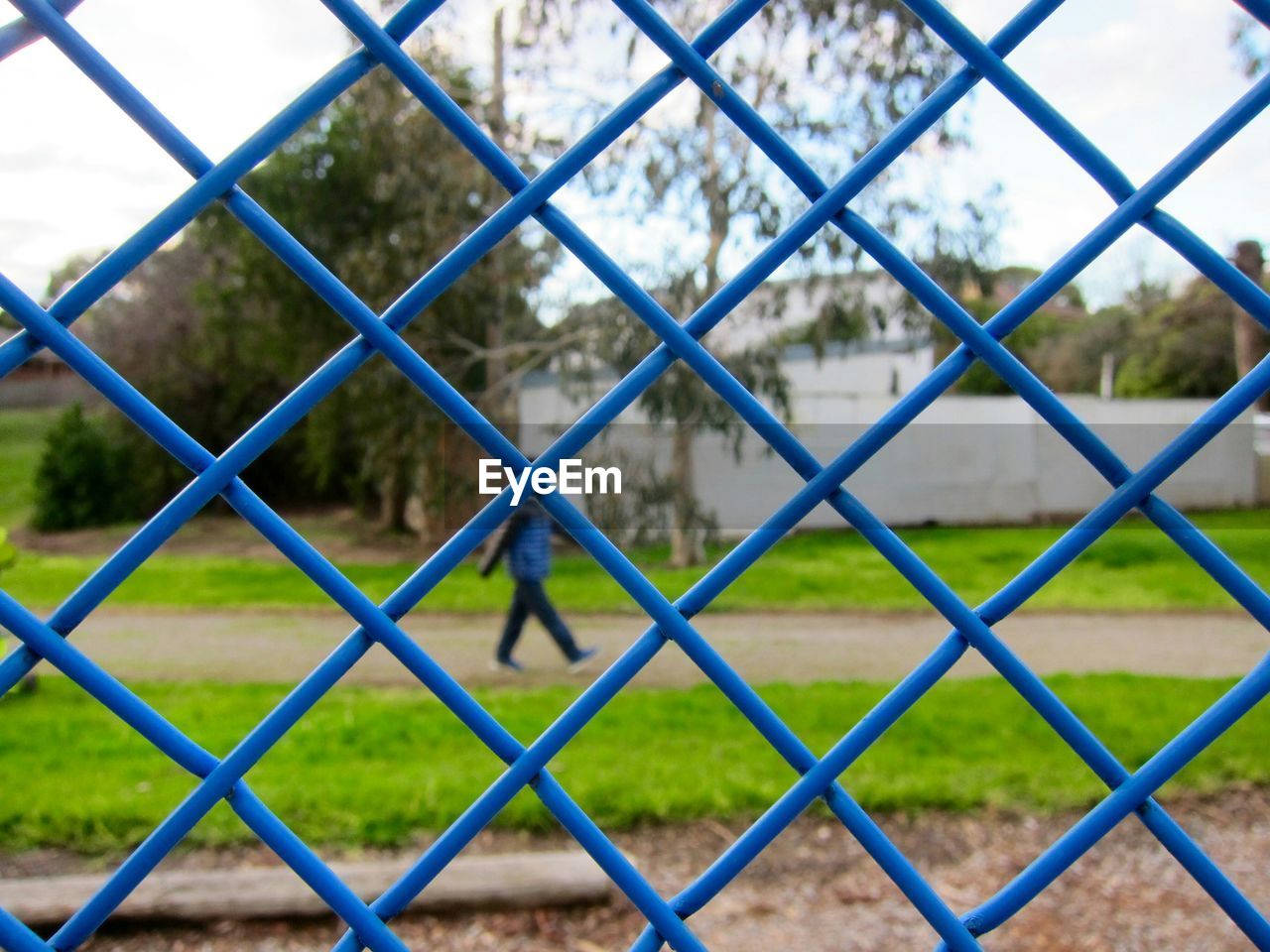 Man walking at park seen through fence
