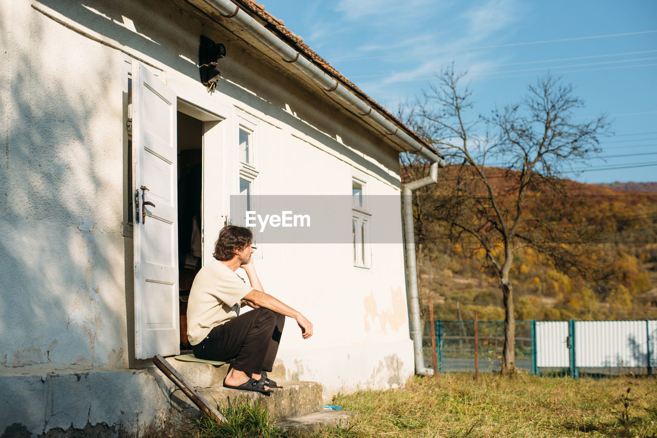 A man sitting near the small house in village. mountains landscape