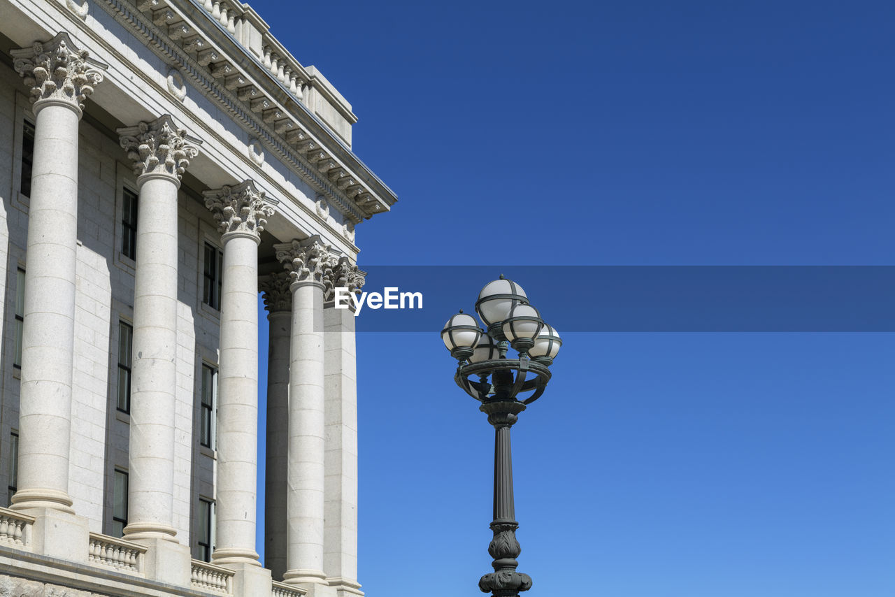 Part of the capitol building with columns and street lamp on blue sky background with copy space