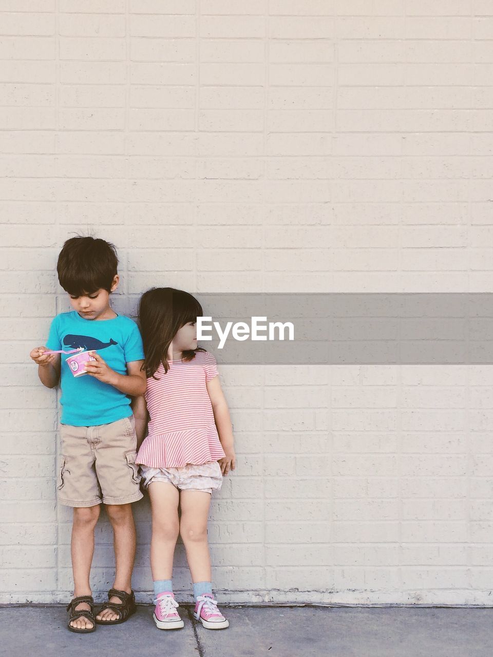 View of two kids standing against the wall