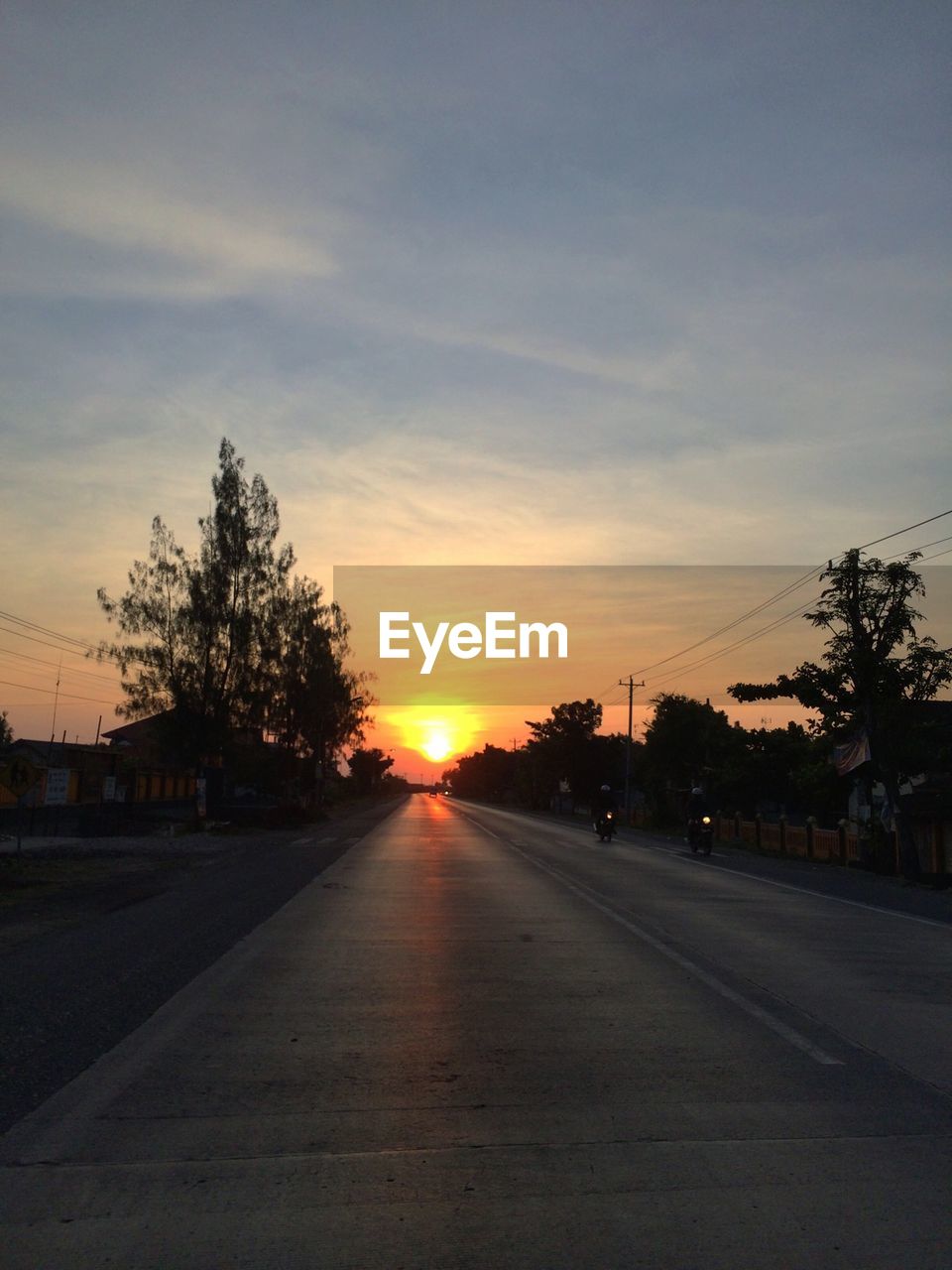 View of road at sunset against cloudy sky