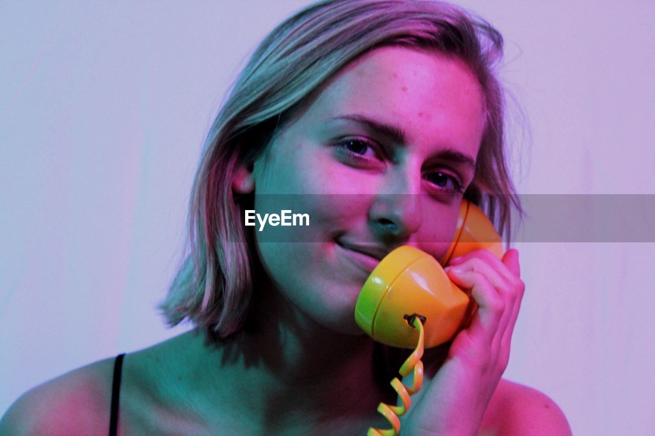 Portrait of smiling beautiful woman talking on yellow telephone