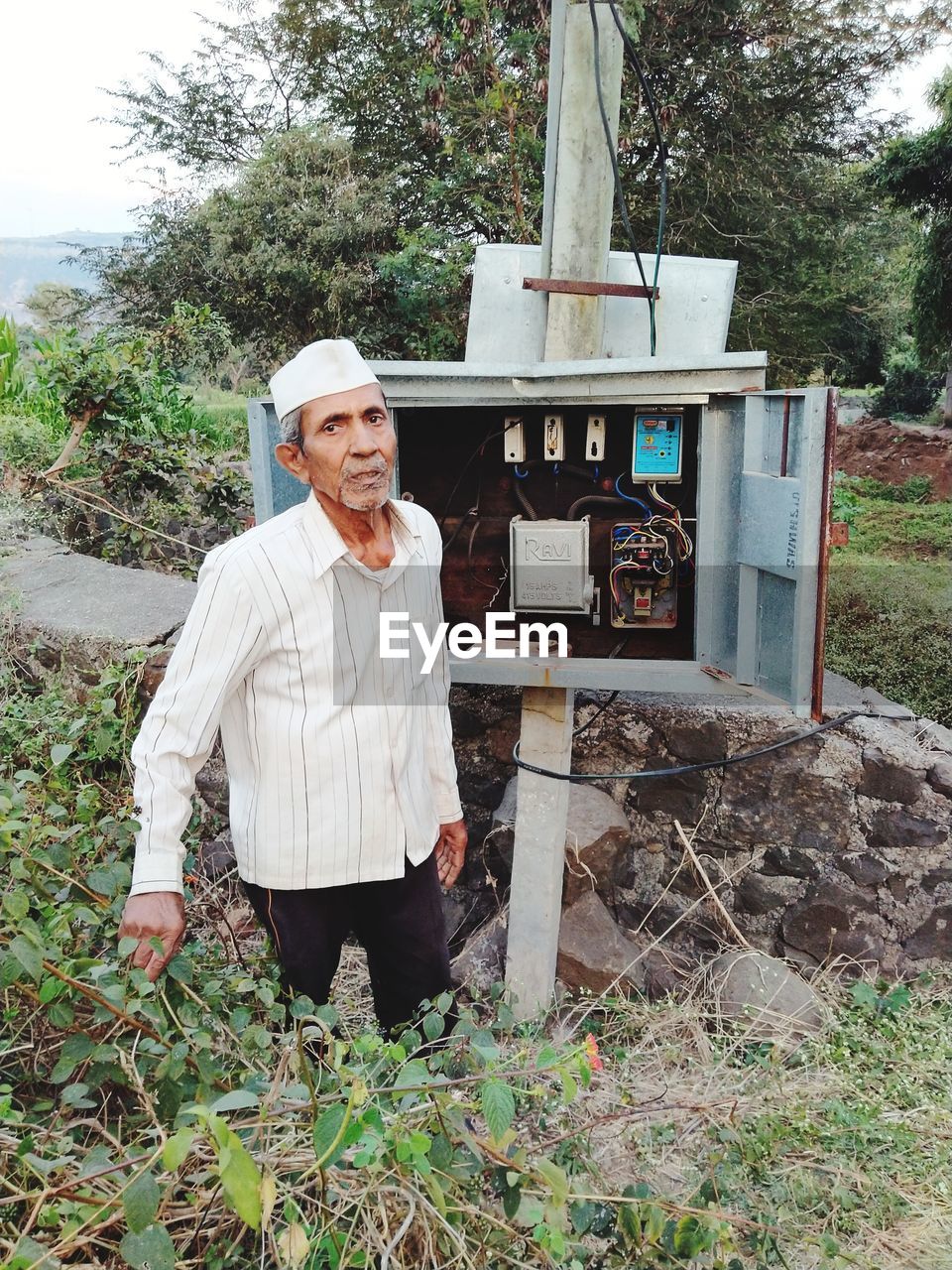 PORTRAIT OF SMILING MAN STANDING AGAINST TREES