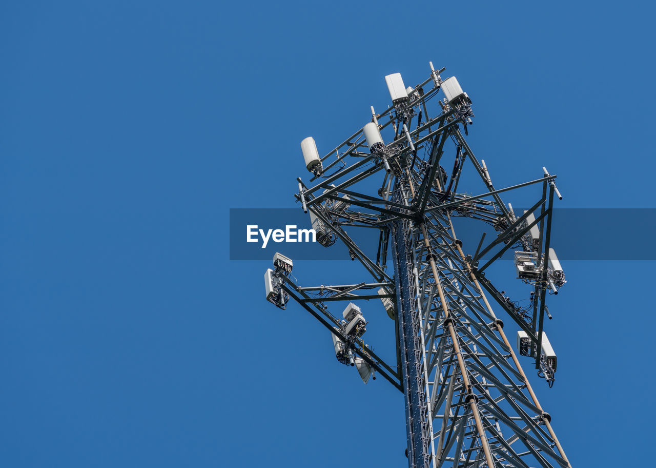 Low angle view of communications tower against blue sky