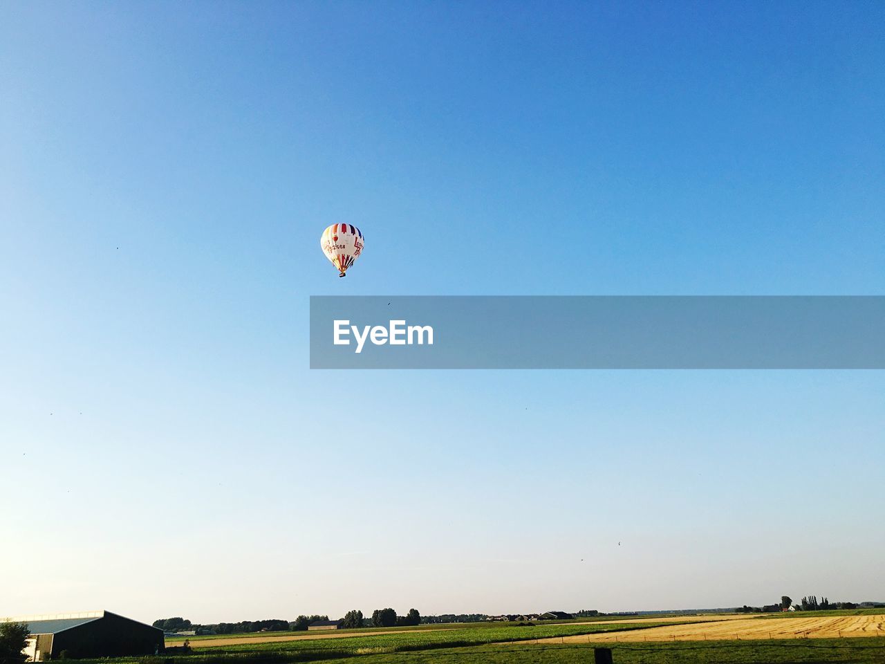 HOT AIR BALLOONS FLYING OVER FIELD AGAINST CLEAR SKY