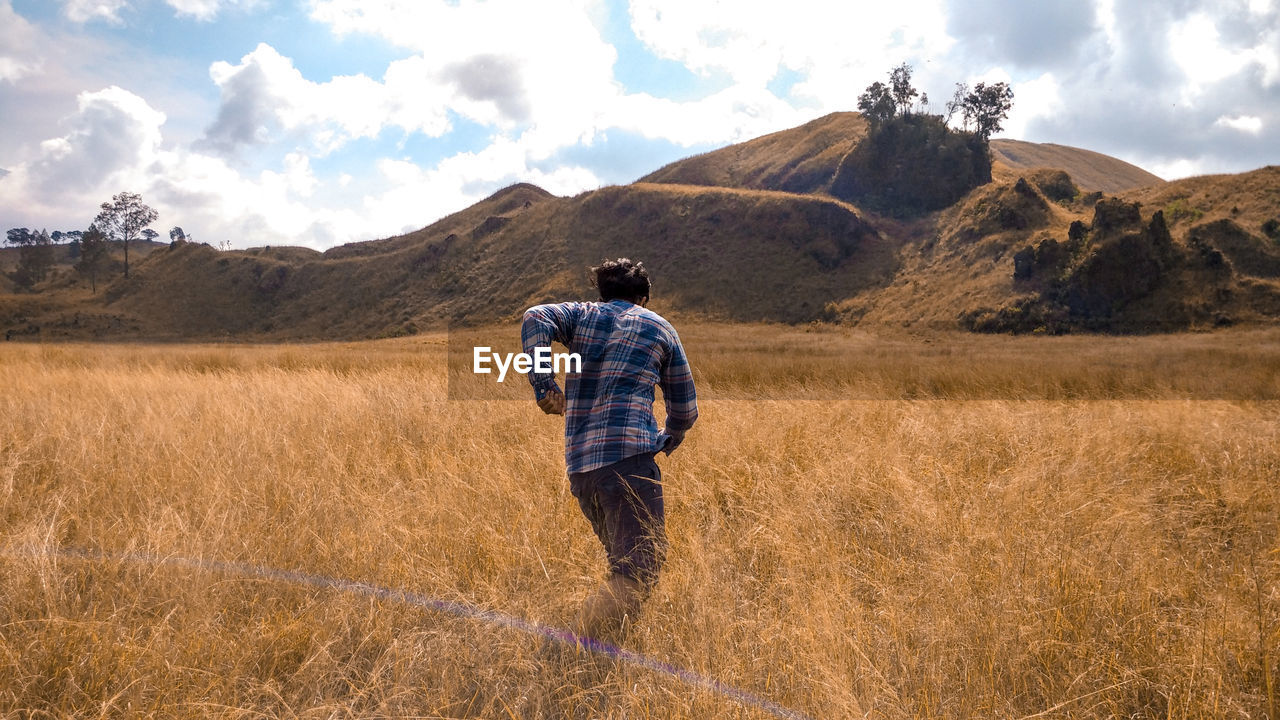 Rear view of man walking on field