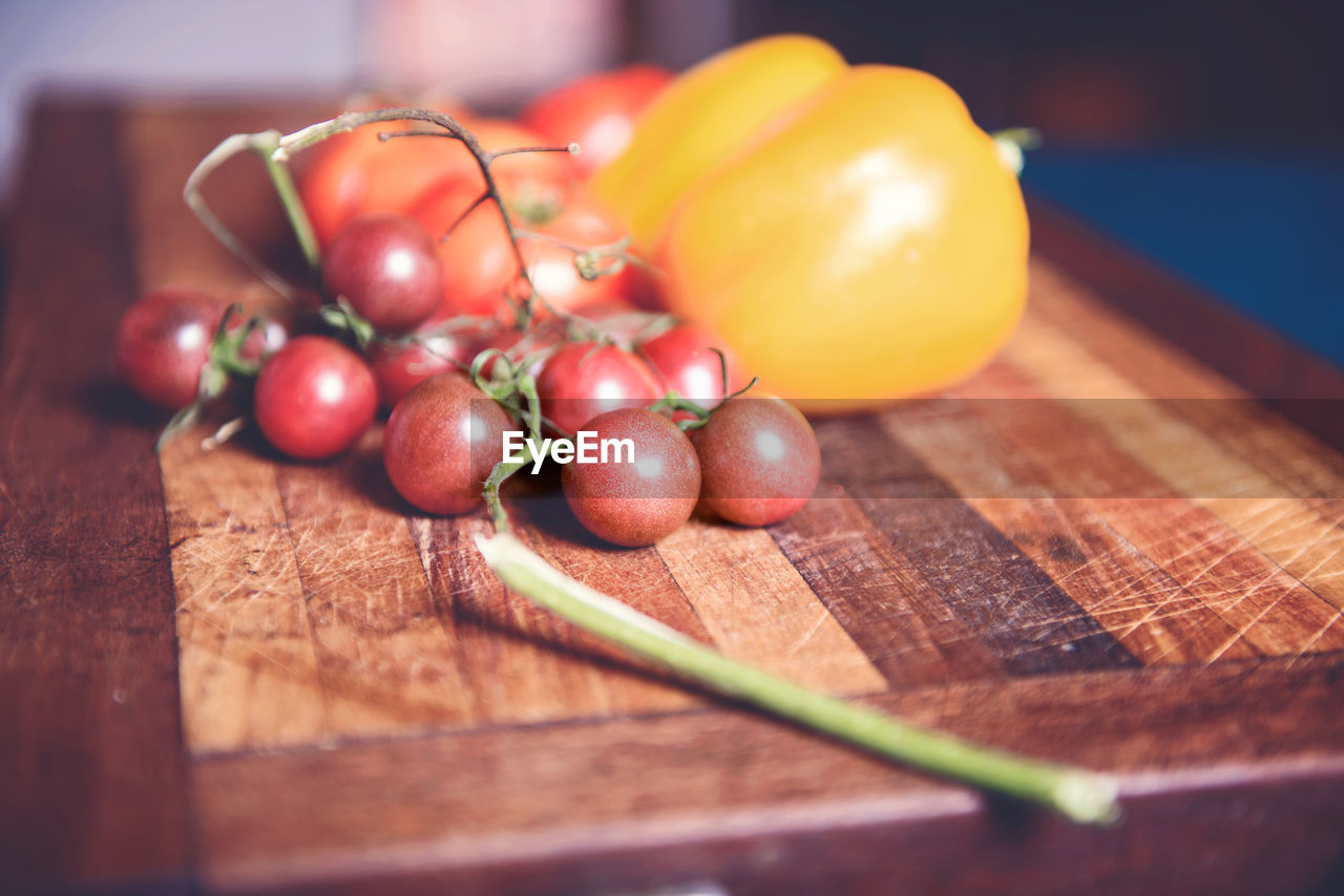 Close-up of cherry tomatoes by yellow bell peppers on table