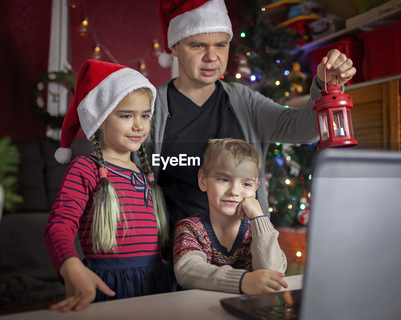 Safe online christmas. happy family in santa red hats celebrating virtually via internet