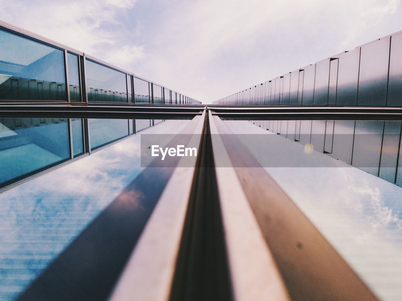 Bridge with reflection over river against sky