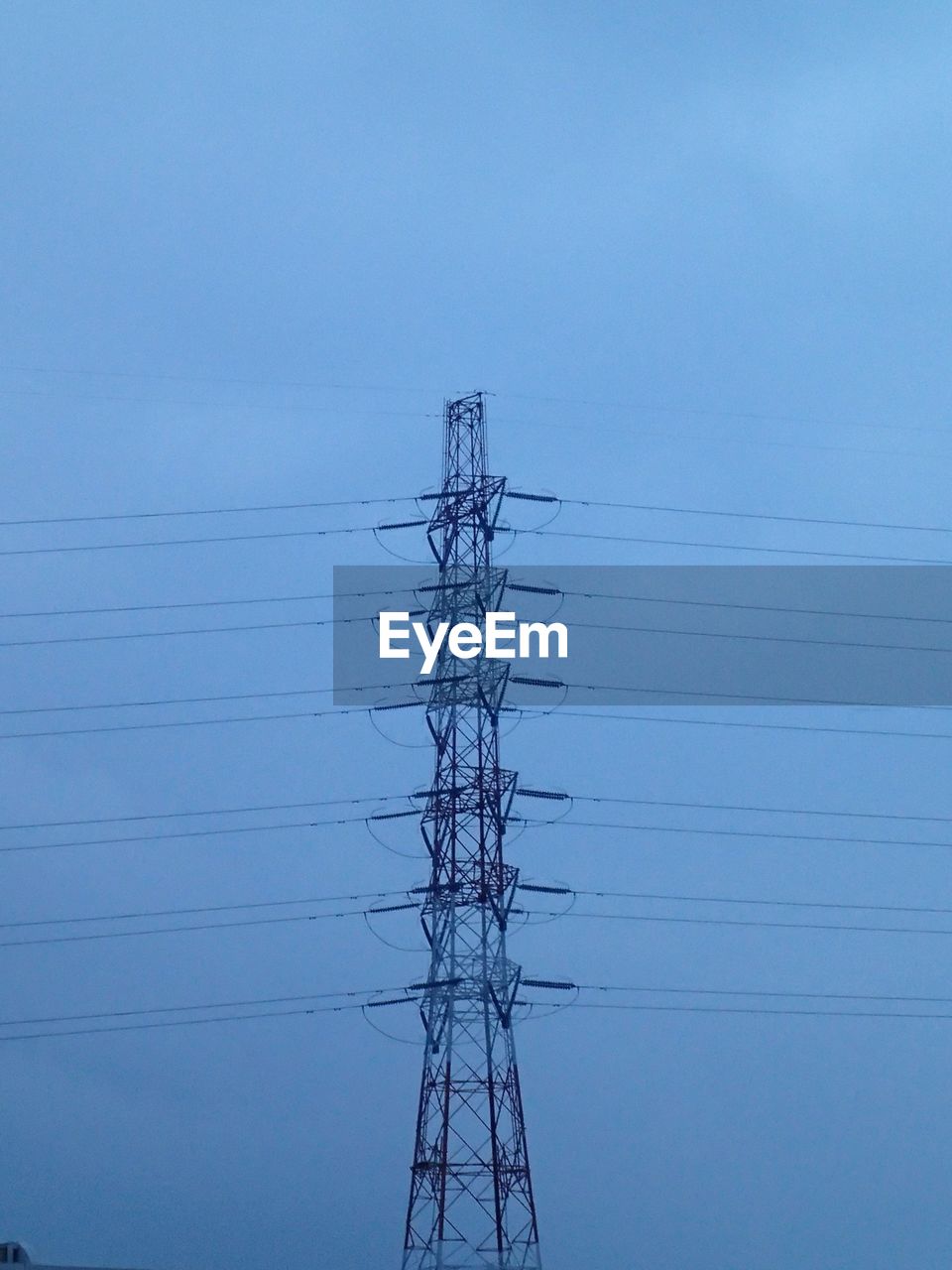 Low angle view of electricity pylon against clear blue sky