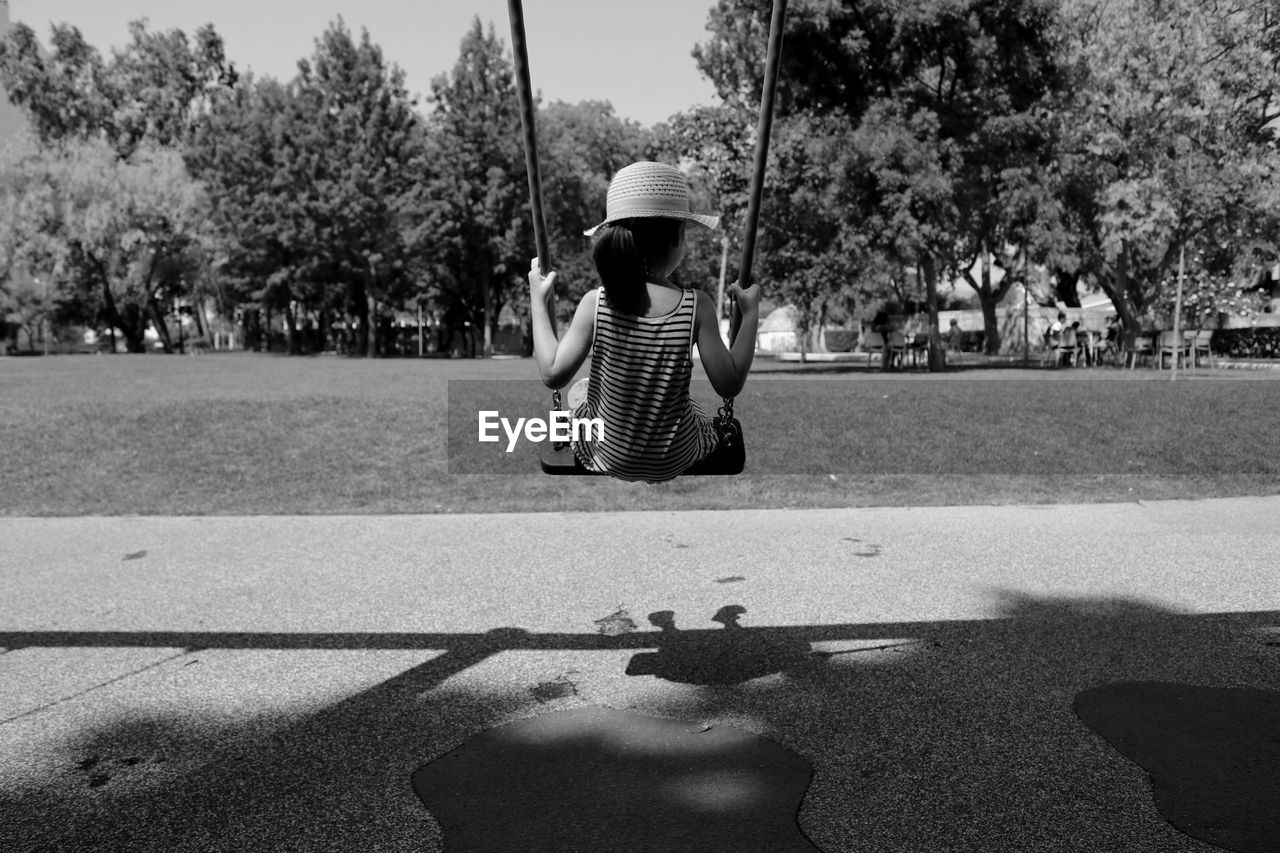 Rear view of girl sitting on swing at playground