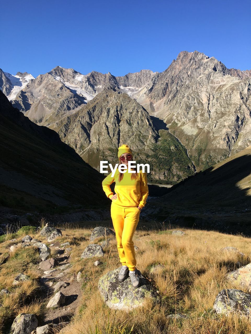 MAN STANDING ON MOUNTAINS AGAINST SKY