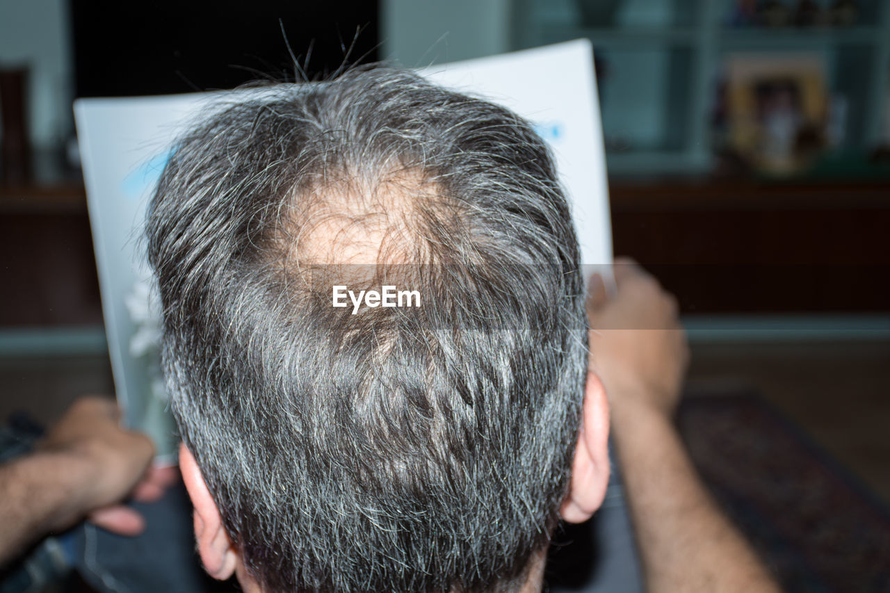 Rear view of man reading paper