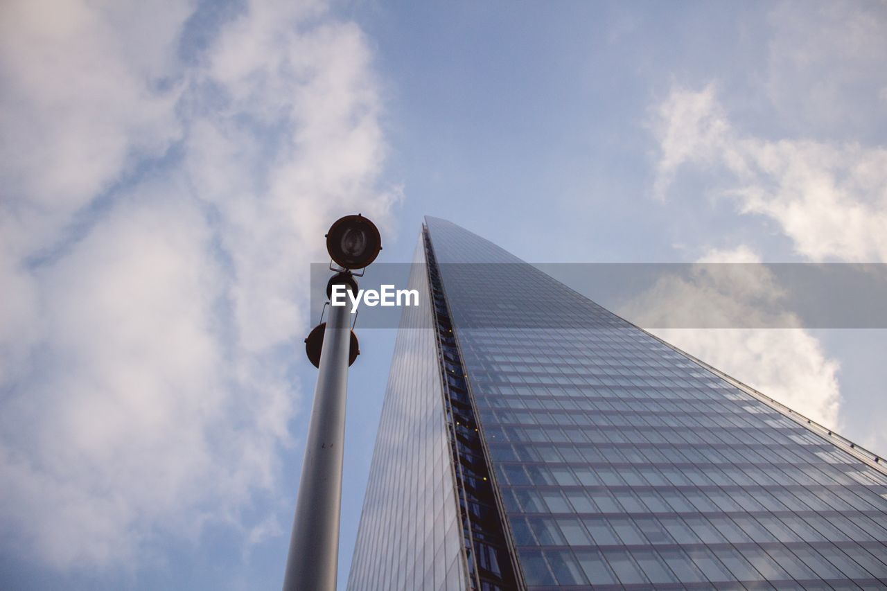 Low angle view of shard london bridge and street light against sky in city on sunny day