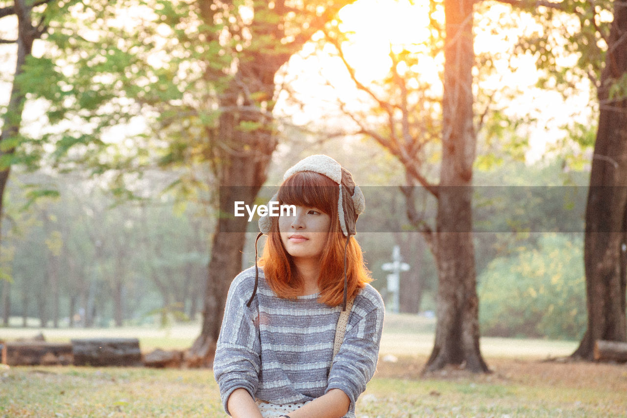 Portrait of beautiful young woman against trees