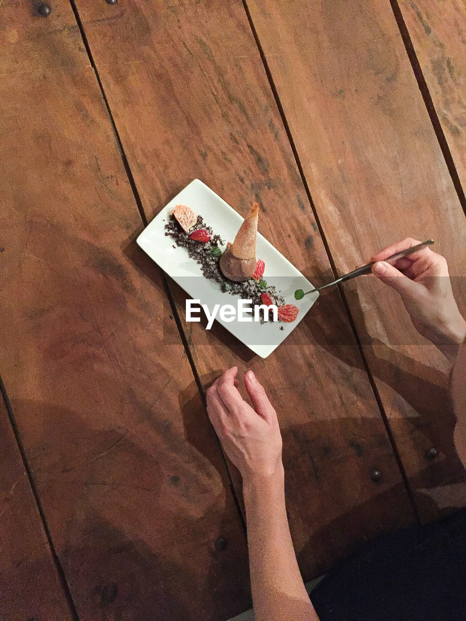 Cropped image of chef preparing dessert in plate on table