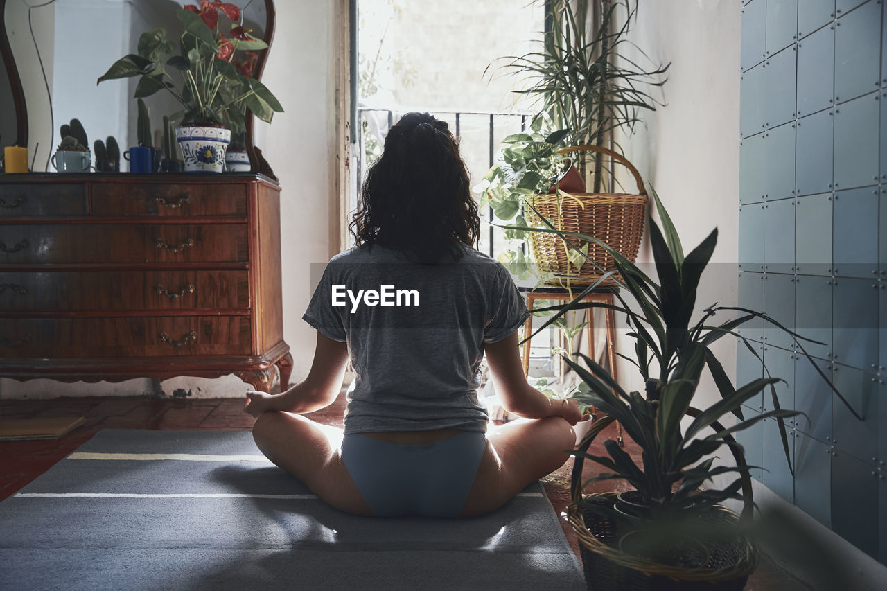 Rear view of woman meditating while sitting at home