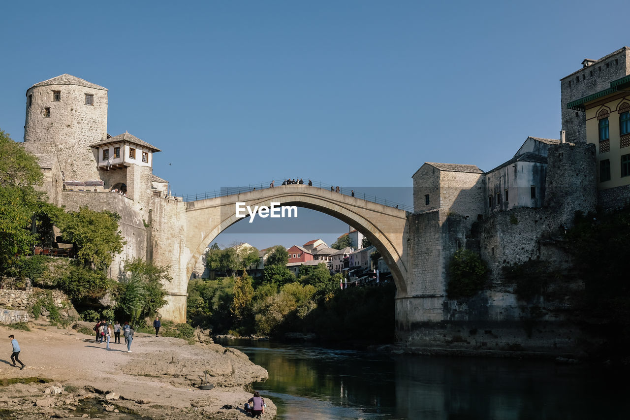 Arch bridge over river against clear sky