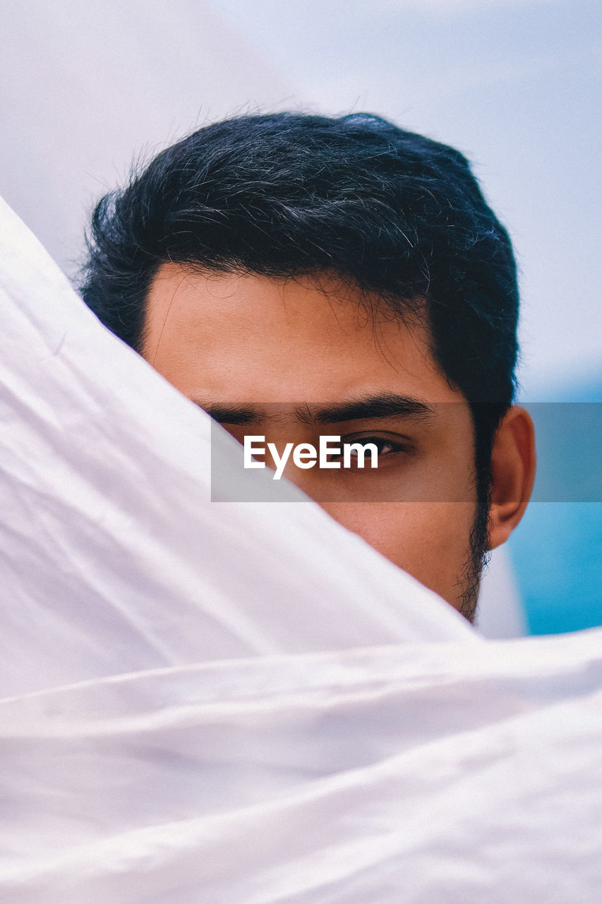 Close-up portrait of handsome young man face covered with sheet