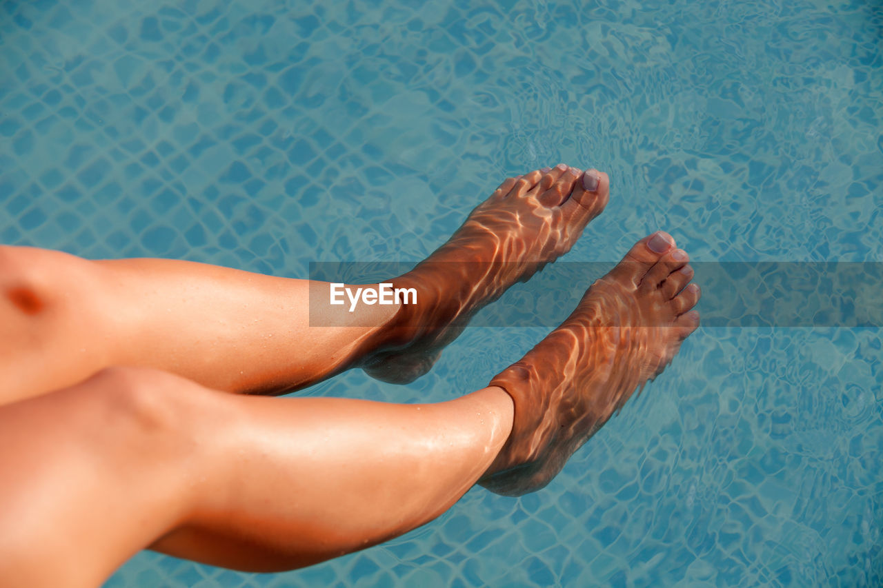 Low section of woman relaxing in swimming pool