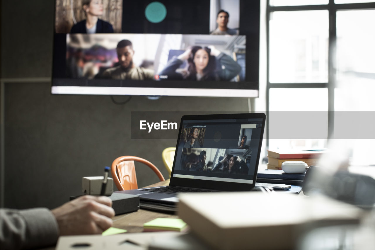 Cropped hand of businessman in meeting with colleagues through video conference at office