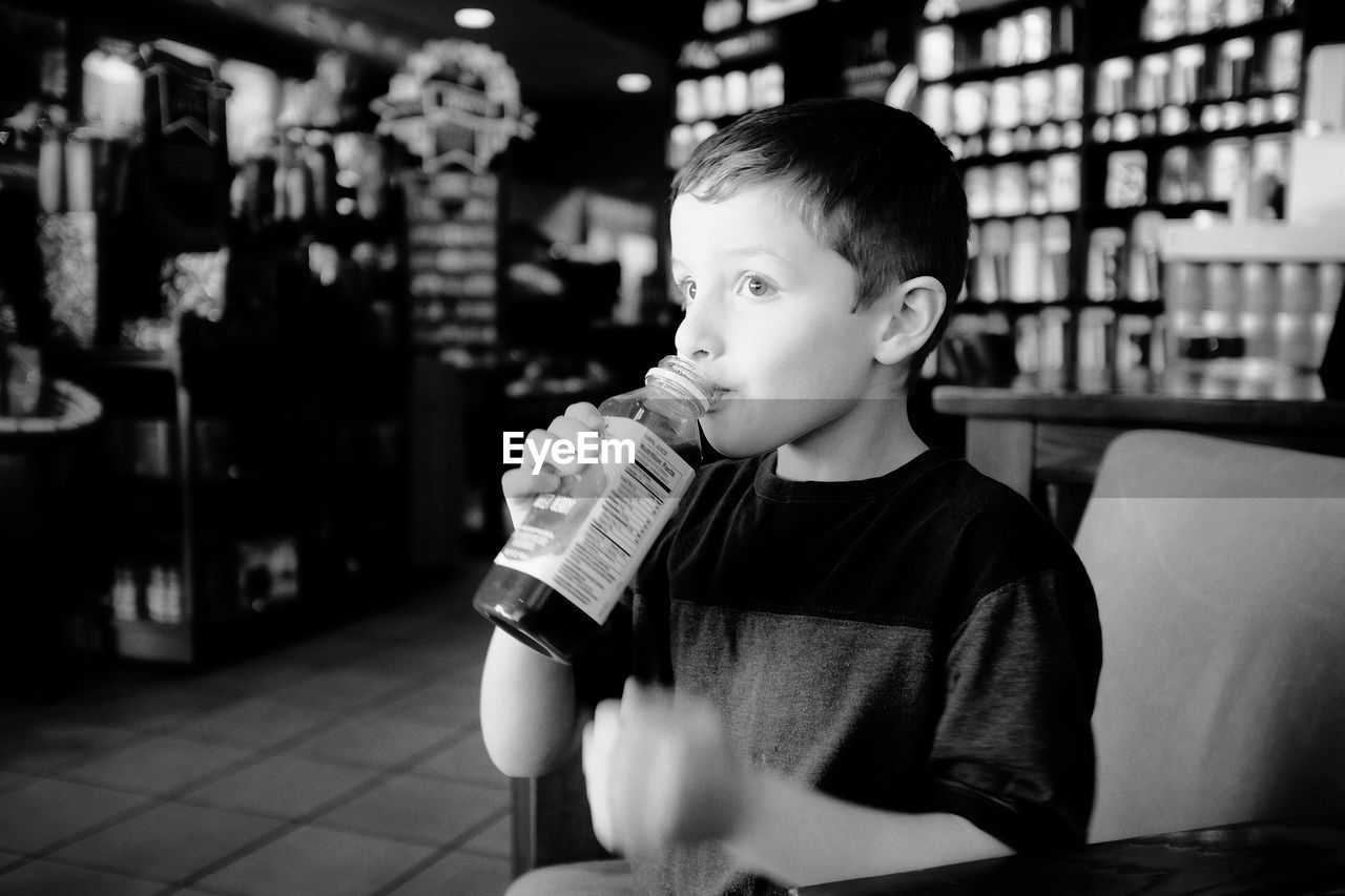 Boy drinking juice while sitting in store
