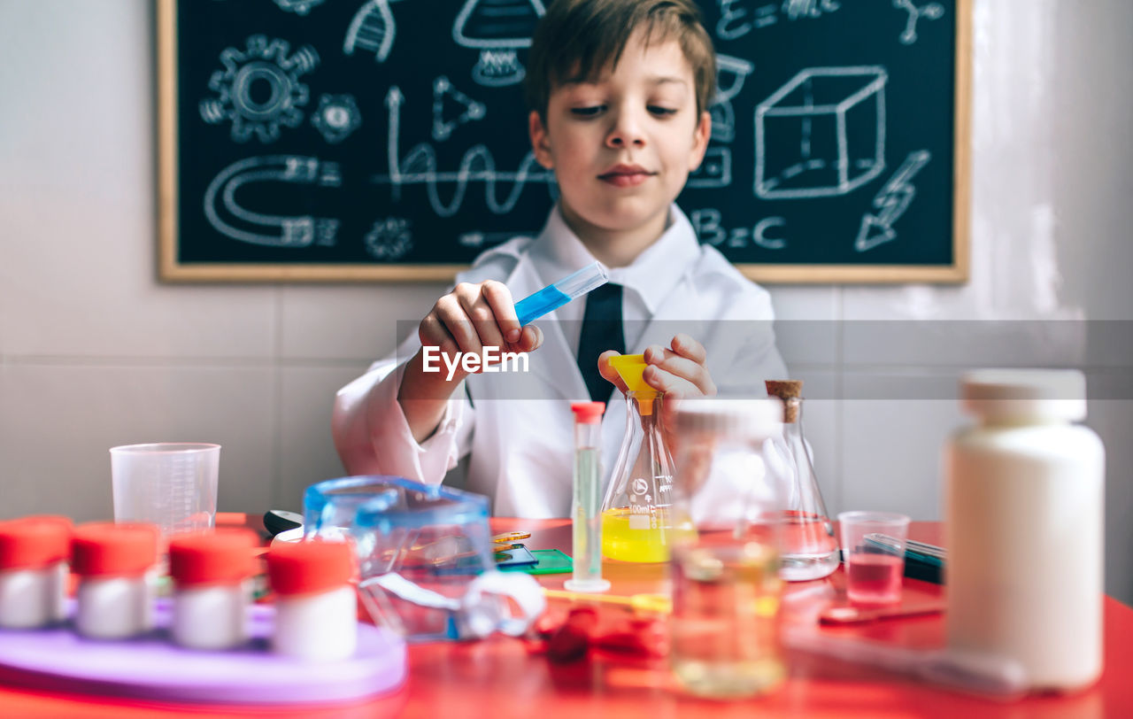 Boy wearing lap coat while sitting in classroom