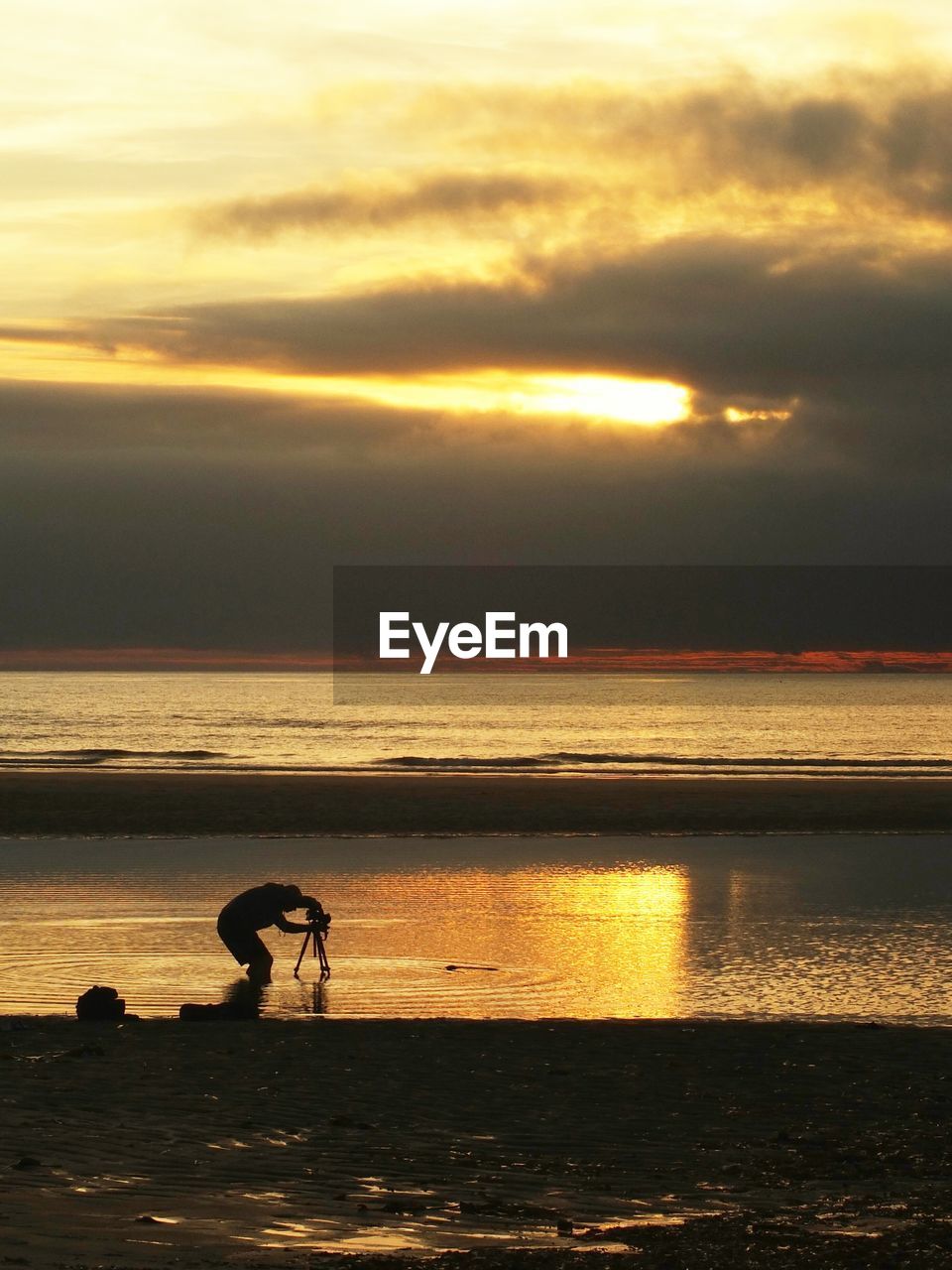 SILHOUETTE MAN IN SEA AGAINST SUNSET SKY