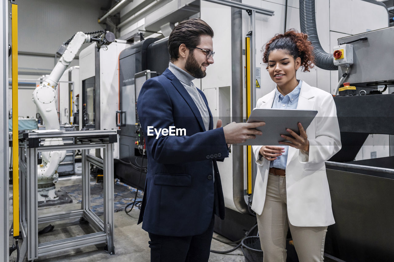 Businessman with colleague discussing over tablet pc in factory