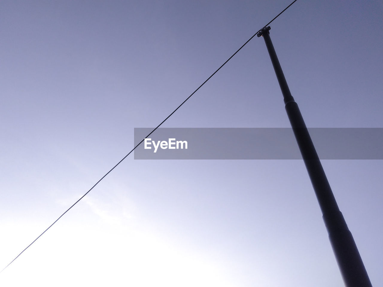 Low angle view of power lines against clear blue sky