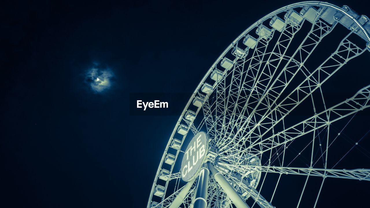 Low angle view of ferries wheel against sky at night