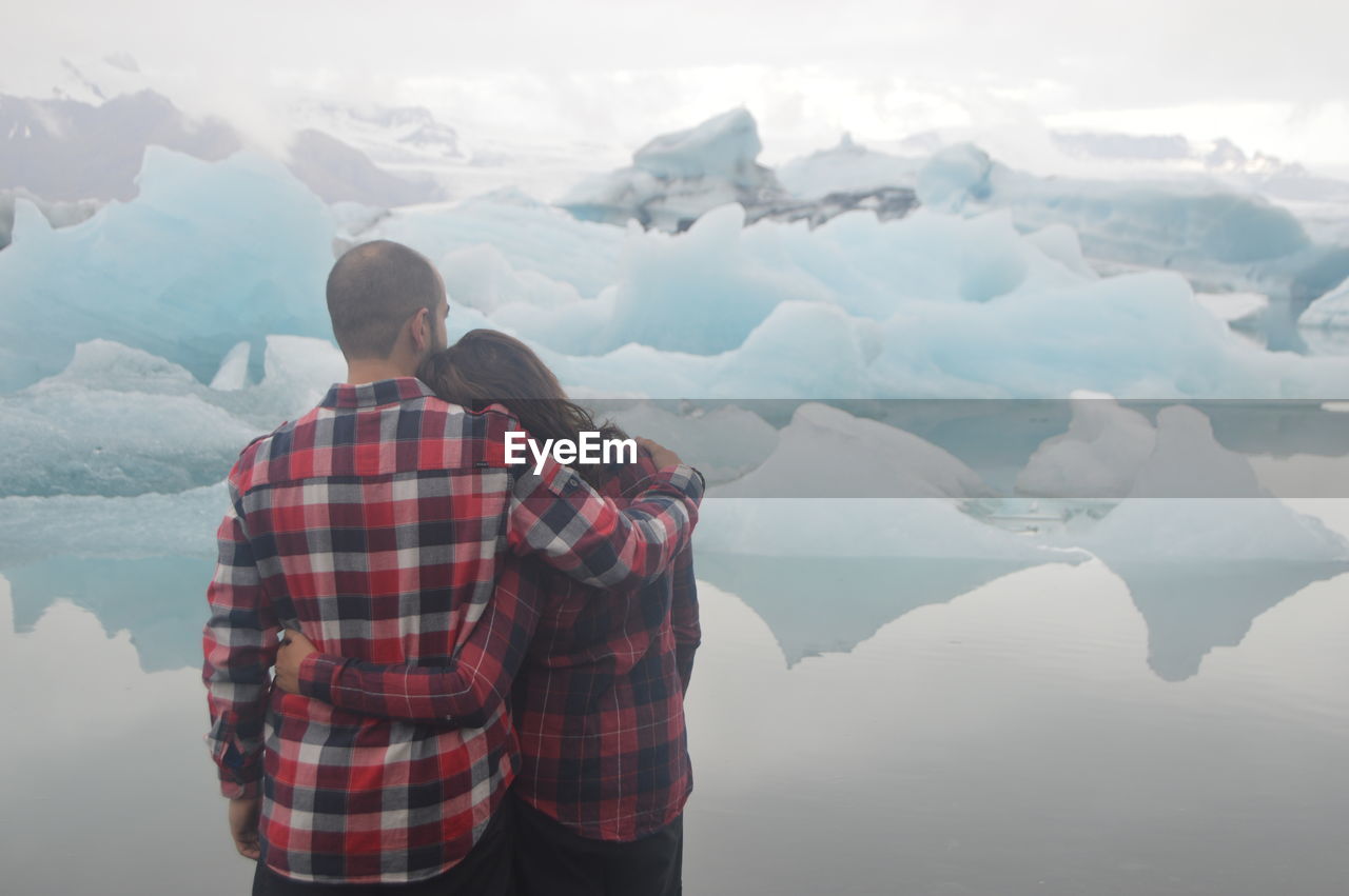 Rear view of couple standing on snow covered mountain